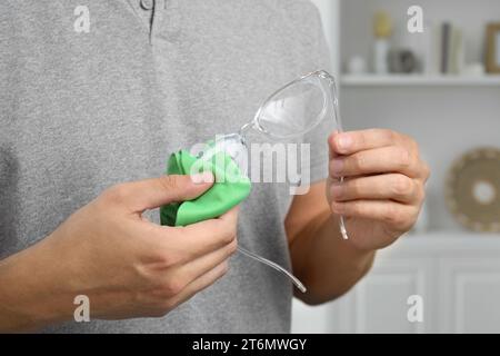 Mann, der drinnen Gläser mit Mikrofasertuch abwischt, Nahaufnahme Stockfoto