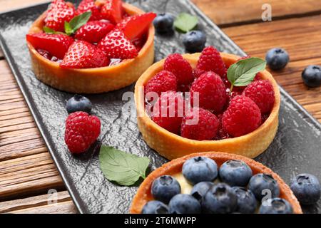 Tartlets mit verschiedenen frischen Beeren auf Holztisch, Nahaufnahme. Köstliches Dessert Stockfoto