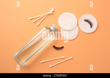 Flache Lay-Komposition mit Make-up-Entferner und falschen Wimpern auf hellorangem Hintergrund Stockfoto