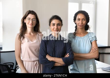 Glückliche, zuversichtliche, schöne, vielfältige Geschäftsfrauen, die zusammen im Büro stehen Stockfoto