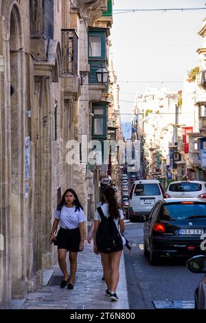 La Valletta, Malta - 17. Juni 2023: Touristen und Autos entlang der bergab Straßen von Valletta, Malta Stockfoto