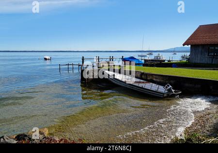 Eine malerische Aussicht mit einem alten Fischerboot auf der Insel Frauenchiemsee oder Fraueninsel auf dem Chiemsee an einem sonnigen Oktobertag in Bayern (Deutschland) Stockfoto