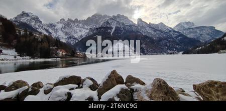 Blick auf den gefrorenen See von Alleghe mit der Stadt im Hintergrund. Stockfoto