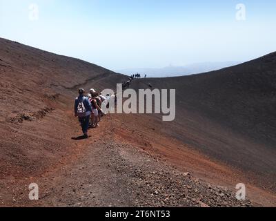 Eine Schlange von Touristen, die in einem vulkanischen Berg (Ätna), Sizilien Italien, unterwegs sind Stockfoto