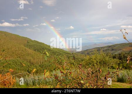 Ein Regenbogen zwischen zwei Bergen in Galicien, Spanien an einem Herbstnachmittag Stockfoto