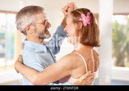 Seniorenpaar, tanzen und glücklich im Haus, Liebe und Ballsaal für Spaß, Berührung und Romantik. Pensionierung, Verbundenheit und Lächeln für Ehemann, Ehefrau und Stockfoto