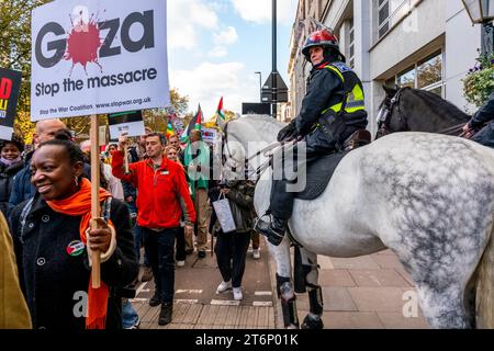 London, Großbritannien. November 2023. Ein berittener Polizeibeamter beobachtet, wie Hunderttausende Demonstranten durch das Zentrum Londons marschieren, um die Bevölkerung von Gaza zu unterstützen. Quelle: Grant Rooney/Alamy Live News Stockfoto