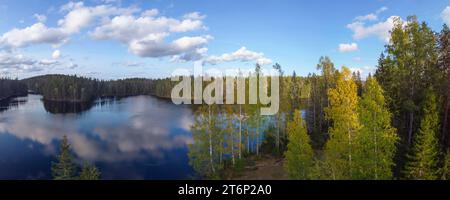See mit reflektierenden Wolken, umgeben von Herbstwald Stockfoto