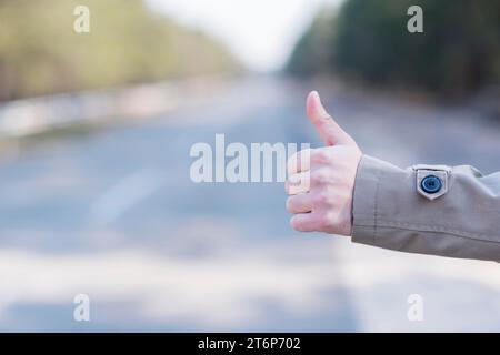 Nahaufnahme der Hand des Mannes per Anhalter auf der Landstraße Stockfoto