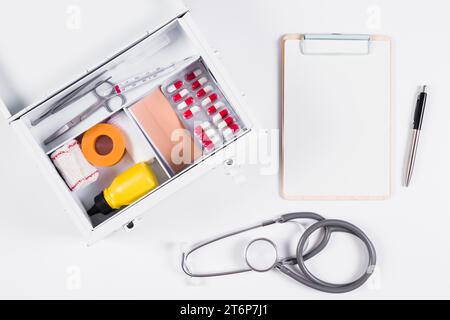 Erste-Hilfe-Kasten mit Clipboard Stethoskop Stift, weißer Hintergrund Stockfoto