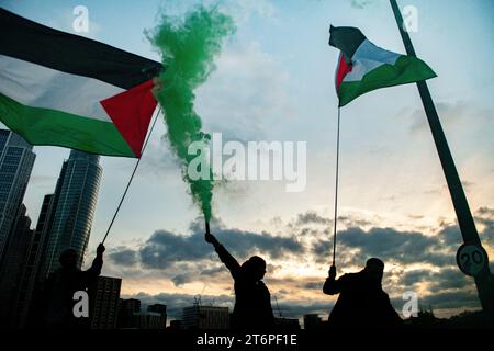 London, Großbritannien. 11. November 2023. In der Abenddämmerung werden Flares auf der Vauxhall Bridge ausgelöst, während palästinensische Anhänger durch London zur US-Botschaft marschieren. Stockfoto