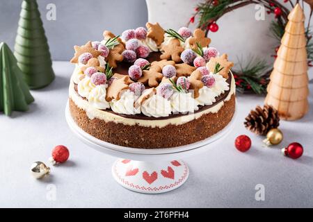 Weihnachtskuchen dekoriert mit Lebkuchenkeksen und gezuckerten Preiselbeeren, festliche Feiertags-Käsekuchen-Idee Stockfoto