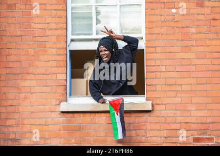 London, UK – 11. November 2023. Eine Frau ruft aus ihrem Fenster zu 300.000 palästinensischen Anhängern, die durch London marschieren Stockfoto