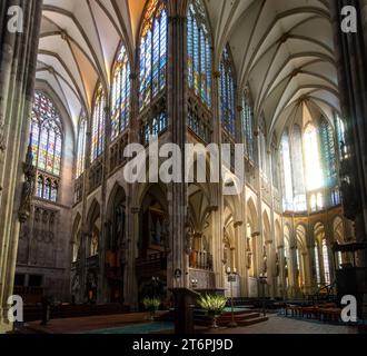 Dieses Bild zeigt eine atemberaubende Kirche mit einem beeindruckenden Innenraum mit mehreren Buntglasfenstern und zwei verzierten Altären Stockfoto