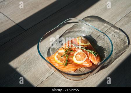 Ein großes saftiges Stück frischer Lachs mit Zitrone und Rosmarin in einer Glasbackform im Ofen Stockfoto