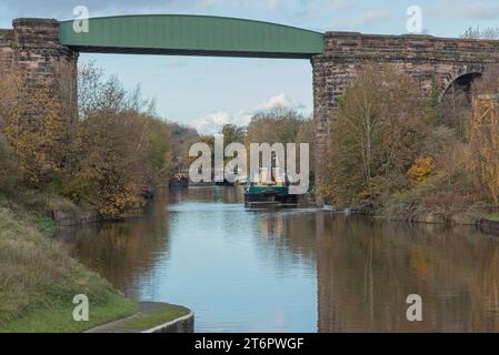 Blick auf den Fluss, wo eine Brücke auf einem Viadukt mit Booten in der Ferne überquert Stockfoto