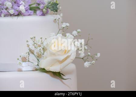 Weiße Hochzeitstorte mit lila und weißen Blumendekorationen aus nächster Nähe Stockfoto