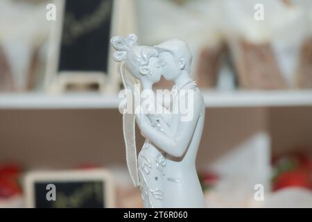 Braut und Bräutigam küssen leidenschaftlich Keramikkuchenauflagen auf dem Kuchen und Infromt von Out of FOCUS Cup Cakes nahe Stockfoto
