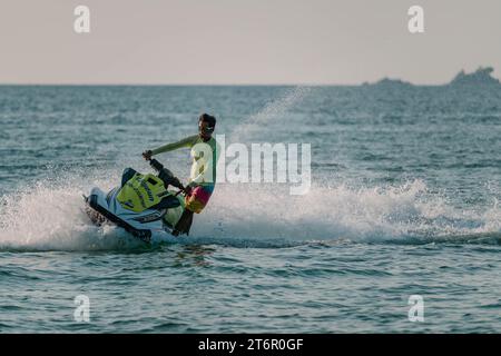 Ein Mann, der an einer Seite des Jetskis steht, wendet sich nach links. PHUKET, THAILAND - 30. APRIL 2023 Stockfoto