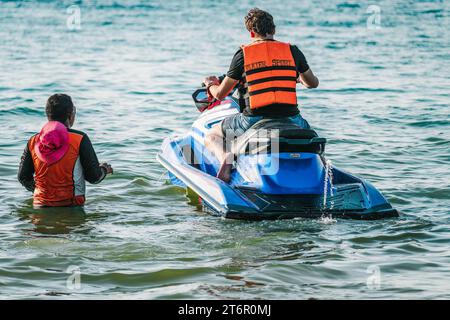 Mann im Meerwasser Folgen Sie langsam fahrenden Jetski mit einem anderen Mann, um zu erklären, wie man Seerooter fährt. Nahaufnahme des Fotos. Stockfoto