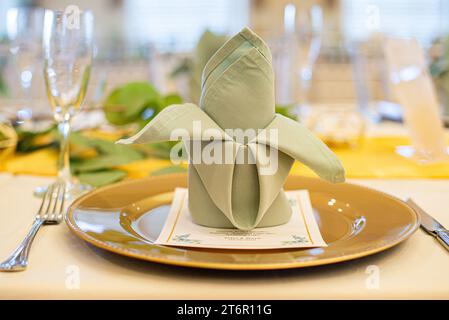 anzegrüne gefaltete Serviette auf Goldteller bei einem wunderschönen Hochzeitsempfang Stockfoto