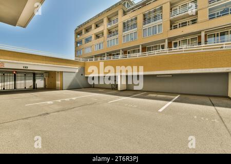 Ein leerer Parkplatz vor einem großen Backsteingebäude mit weißen Linien auf dem Boden und zwei Garagen Stockfoto