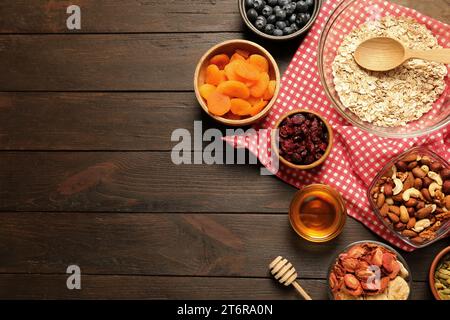 Müsli machen. Haferflocken, getrocknete Früchte und andere Zutaten auf Holztisch, flach liegend mit Platz für Text Stockfoto