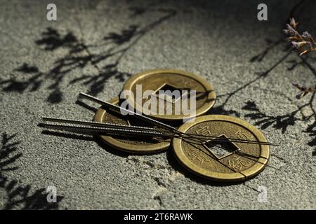 Akupunkturnadeln und alte Münzen auf Steinoberfläche Stockfoto