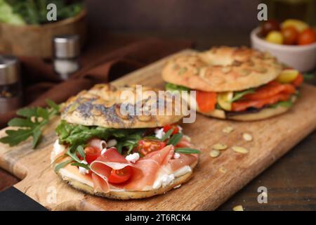 Holzbrett mit leckeren Bagel-Sandwiches auf dem Tisch, Nahaufnahme Stockfoto