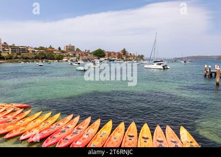 Sydney Harbour at Manly Beach mit Booten im Hafen und einer Reihe oranger Kajaks zum Verleih vom Manly Kajak Centre, NSW, Australien Stockfoto