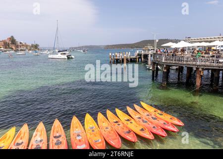 Sydney Harbour at Manly Beach mit Booten im Hafen und einer Reihe oranger Kajaks zum Verleih vom Manly Kajak Centre, NSW, Australien Stockfoto