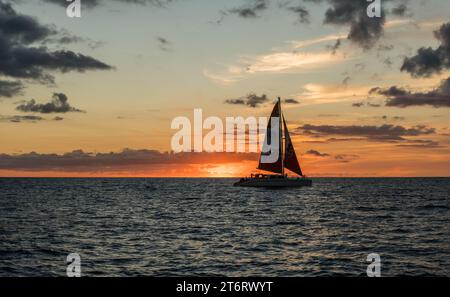 Wunderschöne aussicht auf den Sonnenuntergang mit einem Segelboot im Vordergrund vor der Küste von Honolulu auf Oahu, Hawaii Stockfoto