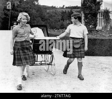 Aktenfoto vom 09/60 von Prinzessin Anne, 10, und Prinz Charles, 11, die die Aufgabe teilen, den Kinderwagen des kleinen Bruders Prinz Andrew für einen Spaziergang auf dem Gelände von Balmoral zu ziehen. Fotos aus jedem Jahr des Königs wurden von der Nachrichtenagentur PA zusammengestellt, um König Karl III. 75. Geburtstag zu feiern. Ausgabedatum: Sonntag, 12. November 2023. Stockfoto