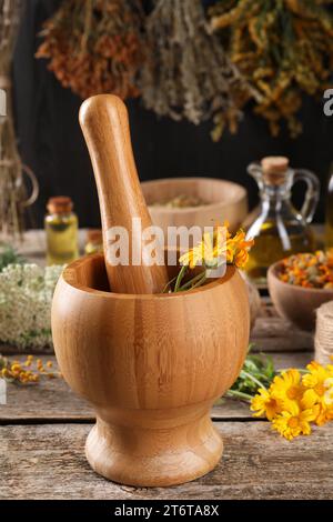 Mörtel mit Stößel und Ringelblumen auf Holztisch. Heilkräuter Stockfoto