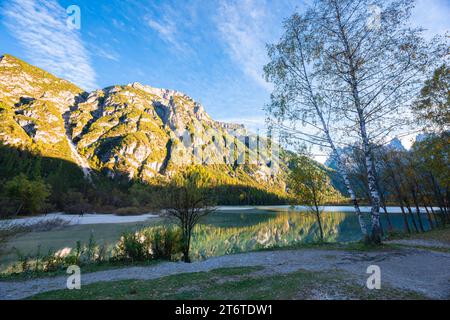 Wunderschöner sonnendurchfluteter Berg entlang des ruhigen Wassers eines Sees in den Dolomiten Stockfoto