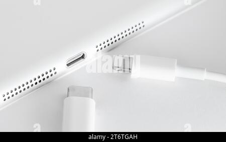 Einheitliches USB-C-Konzept für alle Mobiltelefone. USB-C- und Lightning-Kabel. USB-C-Kabel und Lightning-Kabel vor dem Gerät. Selektiver Fokus. Stockfoto