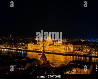 Das prächtige ungarische Parlamentsgebäude ist mit einem wunderschönen, goldenen Glanz beleuchtet, während es majestätisch in der Nacht im Herzen von Budapest steht Stockfoto