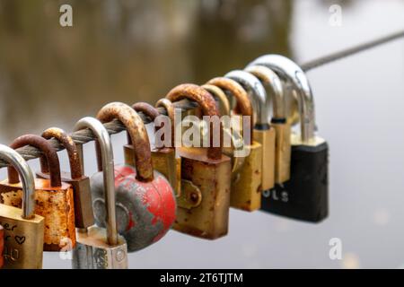 Eine Schnur mit vielen Schlüsseln, die an einem Metallseil mit braunem Aqua-Hintergrund befestigt sind Stockfoto