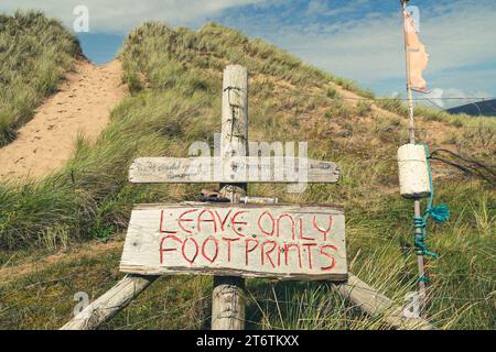 Ein handgemaltes Schild weist darauf hin, dass man nur Fußspuren auf dem Weg zum Strand in Gower, Südwales Großbritannien, hinterlässt Stockfoto