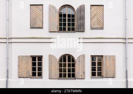 Weiße Gebäudewand mit vielen Bogenfenstern und Holzläden Stockfoto