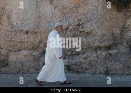 Ein Mann der islamischen Gemeinde der Altstadt Jerusalems spaziert am Freitagsgebete um die Mauern. Jerusalem ist eine heilige Stadt für drei monotheistische Religionen: Judentum, Christentum und Islam. Diese religiöse Vielfalt hat zu einem Zusammenleben geführt, das sowohl freundlich als auch auffällig ist, obwohl die Situation seit den Anschlägen vom 7. Oktober 2023 etwas angespannt geworden ist. Trotz der Konflikte, die die Geschichte der Stadt geprägt haben, haben die Bewohner Jerusalems gelernt, in Harmonie zusammenzuleben. Dies spiegelt sich im Alltag wider, in dem die drei Religionen öffentliche Räume teilen, wie z. B. Stockfoto