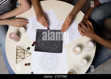 Astrologer zeigt den Kunden ein Zodiakreisrad am Tisch, Draufsicht Stockfoto