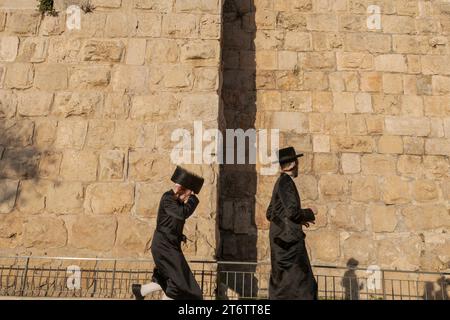 Zwei Männer aus der orthodoxen jüdischen Gemeinde, die durch die Mauern der Altstadt von Jerusalem spazieren. Jerusalem ist eine heilige Stadt für drei monotheistische Religionen: Judentum, Christentum und Islam. Diese religiöse Vielfalt hat zu einem Zusammenleben geführt, das sowohl freundlich als auch auffällig ist, obwohl die Situation seit den Anschlägen vom 7. Oktober 2023 etwas angespannt geworden ist. Trotz der Konflikte, die die Geschichte der Stadt geprägt haben, haben die Bewohner Jerusalems gelernt, in Harmonie zusammenzuleben. Dies spiegelt sich im Alltag wider, in dem die drei Religionen öffentliche Räume teilen, wie die Alte Stockfoto