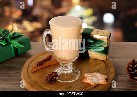 Ein Glas köstlicher Eierlikör, Gewürze, Kekse und Geschenkboxen auf einem Holztisch in der Bar Stockfoto