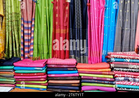 Schicke indische Sarees, fein säuberlich gestapelte bunte Seidensaris in Regalen in einem Textilgeschäft. Unglaubliches Indien. Stockfoto