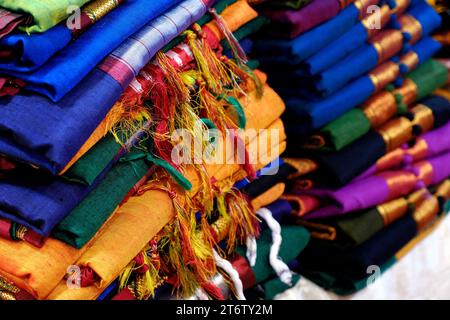 Schicke indische Sarees, fein säuberlich gestapelte bunte Seidensaris in Regalen in einem Textilgeschäft. Unglaubliches Indien. Stockfoto