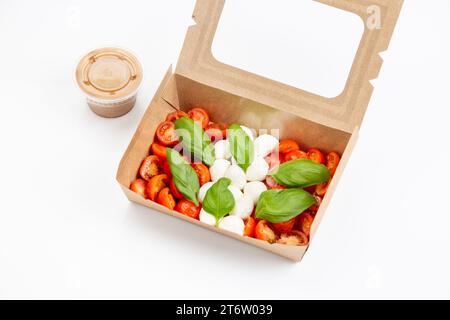 Eine farbenfrohe und einladende Szene mit einer Holzkiste voller frischer Tomaten und Mozzarella, begleitet von einer dampfenden Tasse Kaffee Stockfoto