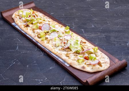 Ein frisch gebackenes Stück Pizza im italienischen Stil auf einem rustikalen Holzbrett, garniert mit geschmolzenem Käse und herzhaften Belägen Stockfoto