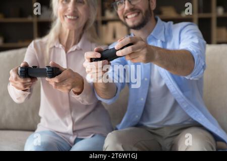Junge Männer haben Spaß beim Spielen von Videospielen mit älterer Mutter Stockfoto