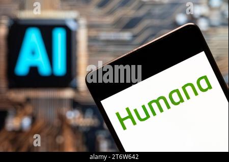 In dieser Fotoabbildung wird das Logo der amerikanischen Krankenkasse Humana (NYSE: HUM) auf einem Smartphone mit einem Chip für künstliche Intelligenz (KI) und einem Symbol im Hintergrund angezeigt. Stockfoto